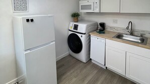 Una cocina compacta equipada con lavadora, microondas y refrigerador.