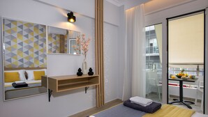 A modern hotel room with a bed, a bedside table, a mirror, and a view of the balcony. - City Centre Gem in Chania (Χανιά)