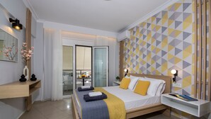 A modern hotel room with a large bed, bedside tables, a desk, and a balcony with a view. - City Centre Gem in Chania (Χανιά)