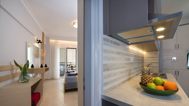 A modern kitchen with a fruit bowl, a red chair, and a wooden counter. - City Centre Gem in Chania (Χανιά)