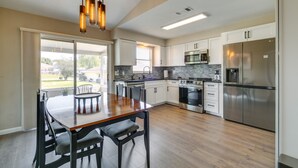 A modern kitchen with a central island, stainless steel appliances, and a large window providing natural light. - Florida Vacation Rental w/ Enclosed Porch! (Beverly Hills)