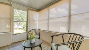 A room with a sliding glass door, a round table with a potted plant, and two chairs. - Florida Vacation Rental w/ Enclosed Porch! (Beverly Hills)
