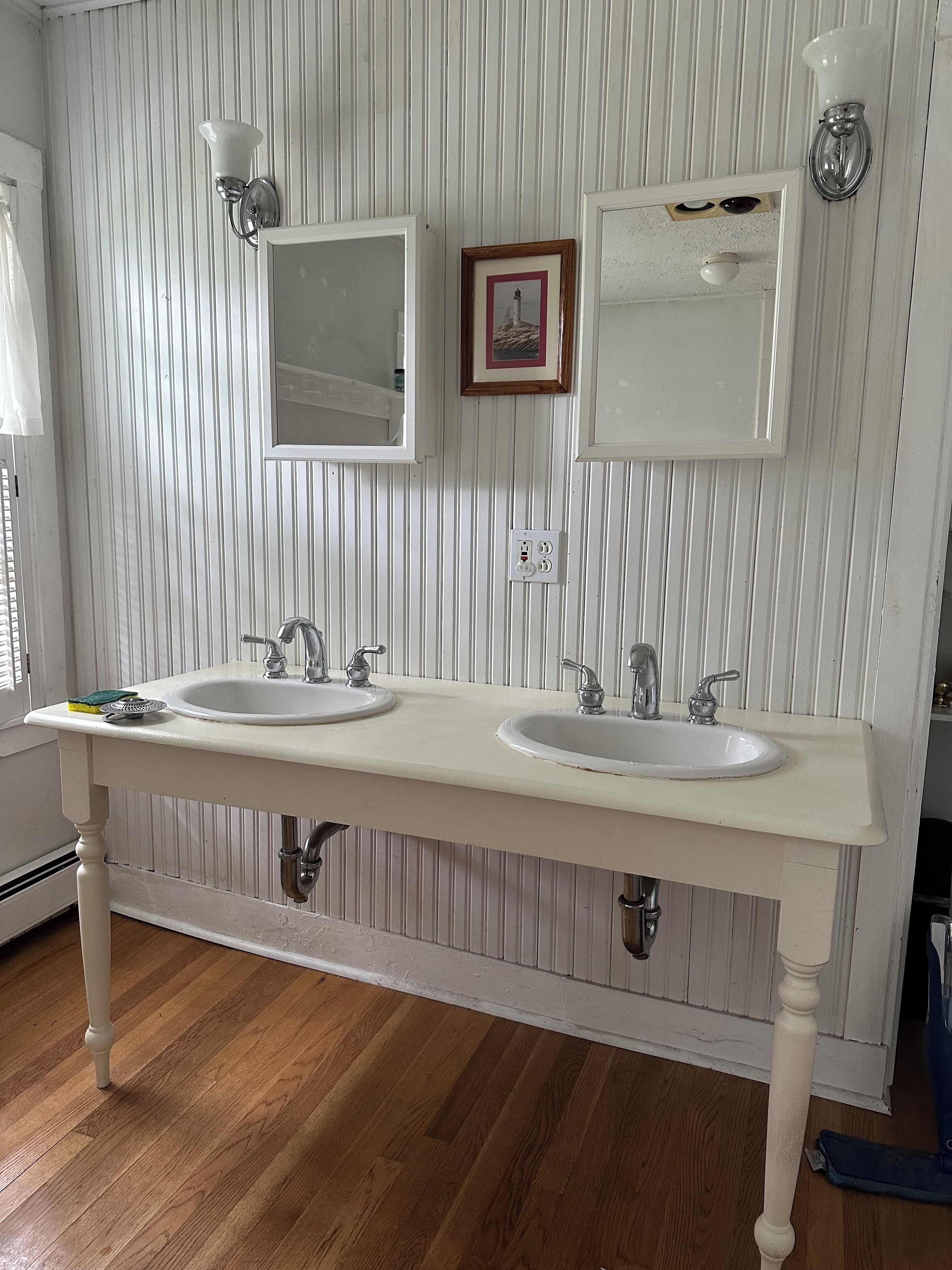 A bathroom with two sinks, a mirror, and a framed picture on the wall.