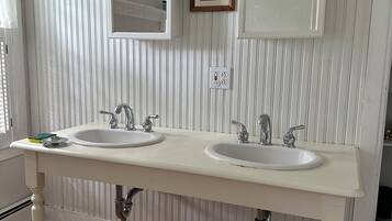 A bathroom with two sinks, a mirror, and a framed picture on the wall.
