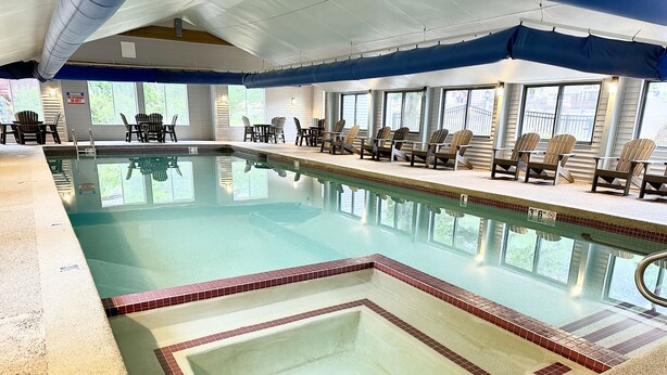 Une piscine intérieure à l’eau claire, dont les bords sont recouverts de carreaux, et qui dispose d’un poste de surveillance pour les sauveteurs.