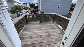 A wooden deck with a railing, a view of neighboring houses, and a cloudy sky.