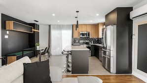 A modern kitchen with stainless steel appliances, a central island, and a dining area with bar stools.