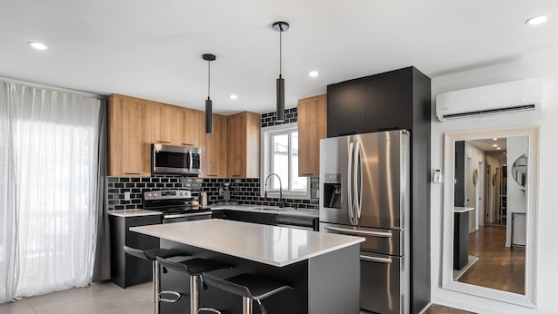 A modern kitchen with a central island, stainless steel appliances, and wooden cabinetry.