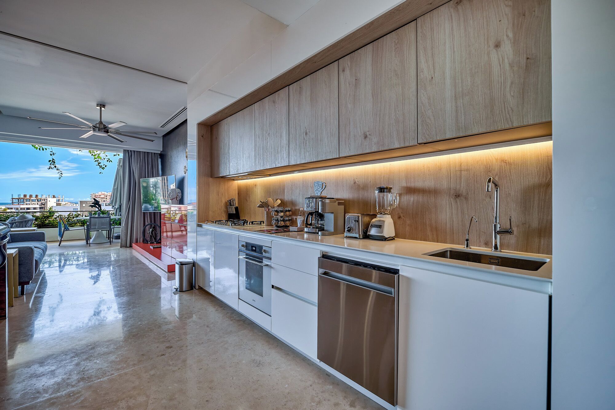 Een moderne keuken met een inbouwoven, vaatwasser en een groot kookeiland met spoelbak.