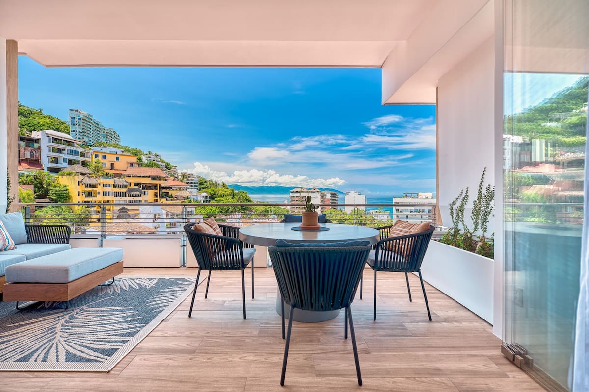 Un balcon avec une table ronde, des chaises et un canapé.