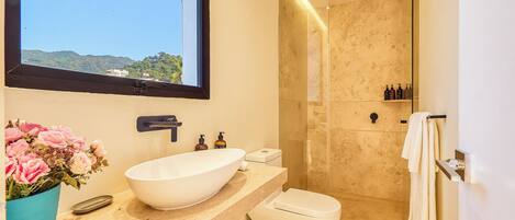 Ein modernes Badezimmer mit großem Fenster, Waschbecken in Weiß, Toilette und Duschbereich.