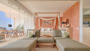 Une chambre à coucher moderne avec une grande fenêtre, un lit à baldaquin et un coin salon agrémenté de coussins.