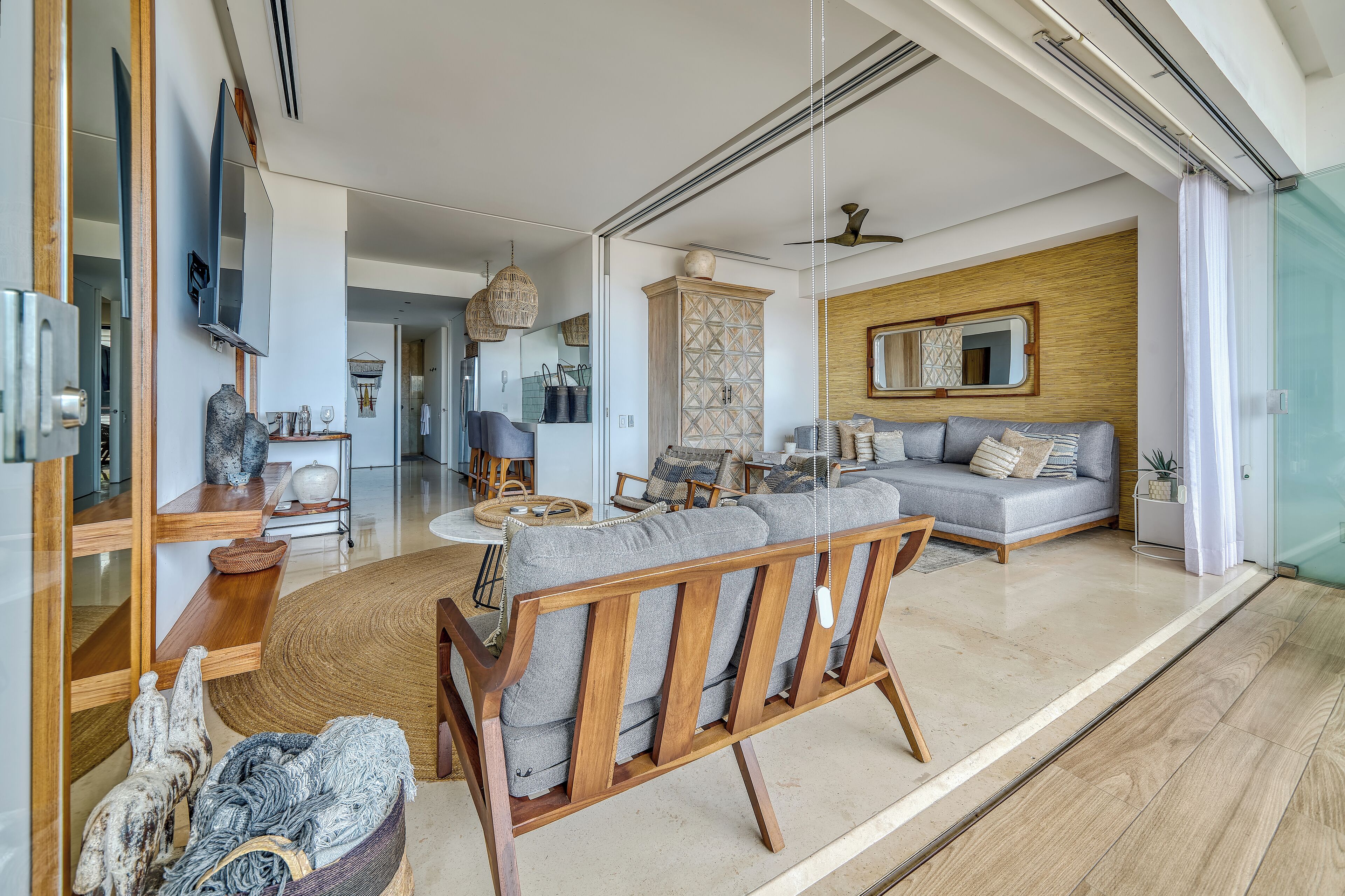 A spacious living area with a sofa, wooden furniture, and a large mirror.