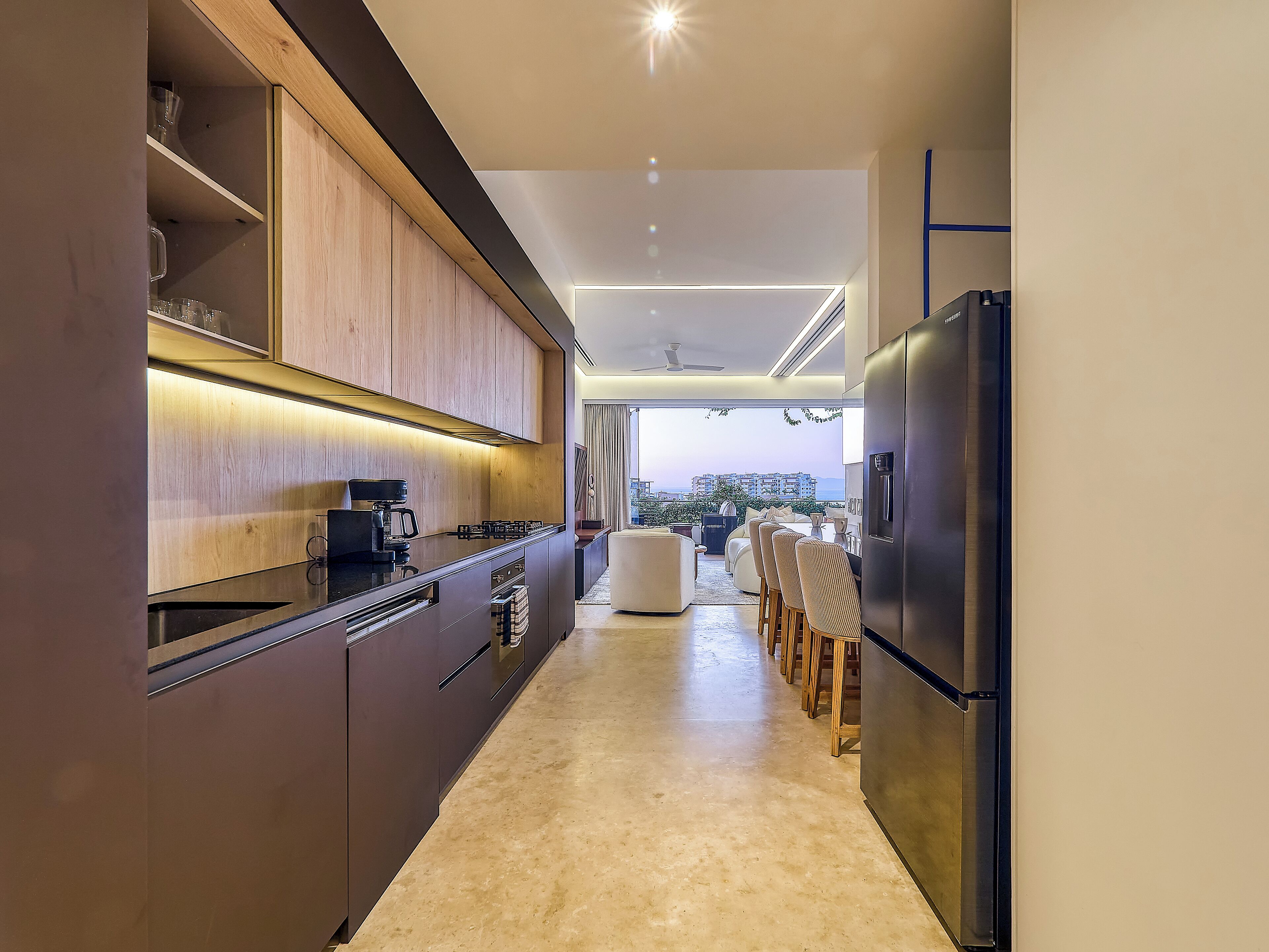 A modern kitchen with dark cabinetry, a built-in stove, and a refrigerator.