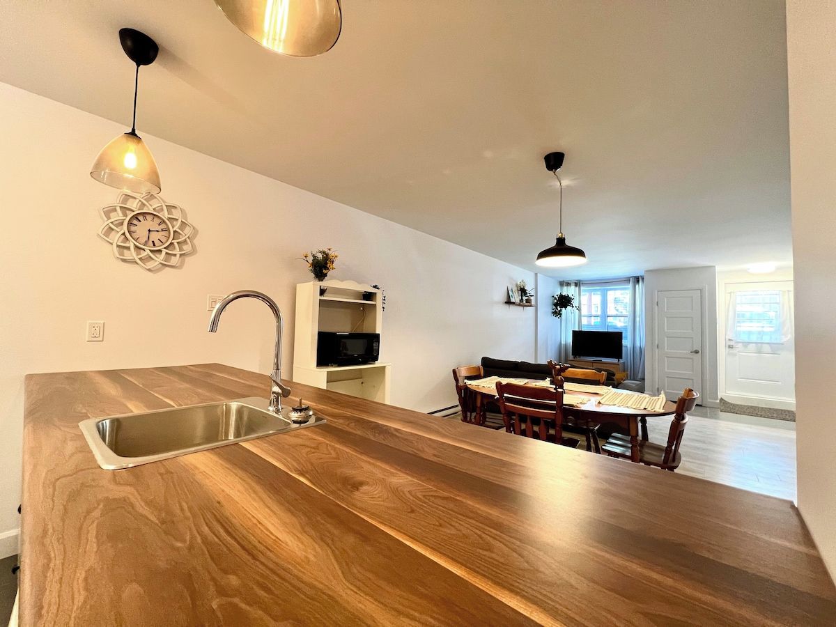 Una cocina moderna con encimera de madera, pileta de acero inoxidable e iluminación colgante.