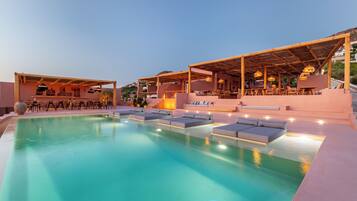 Un área de piscina con sillones reclinables y un bar.
