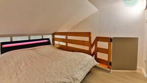 Een slaapkamer met een stapelbed, een hoofdeinde met lichtbalk en een wandbord.