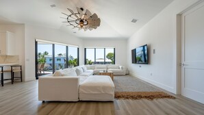 A modern living room with a large sectional sofa, a ceiling fan, and a flat-screen TV mounted on the wall. - ISLAMORADA DREAM (Islamorada)
