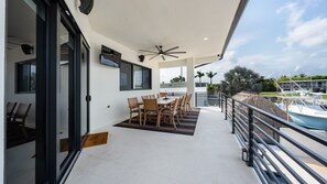 A balcony with a dining table and chairs, a ceiling fan, and a view of a marina with boats. - ISLAMORADA DREAM (Islamorada)