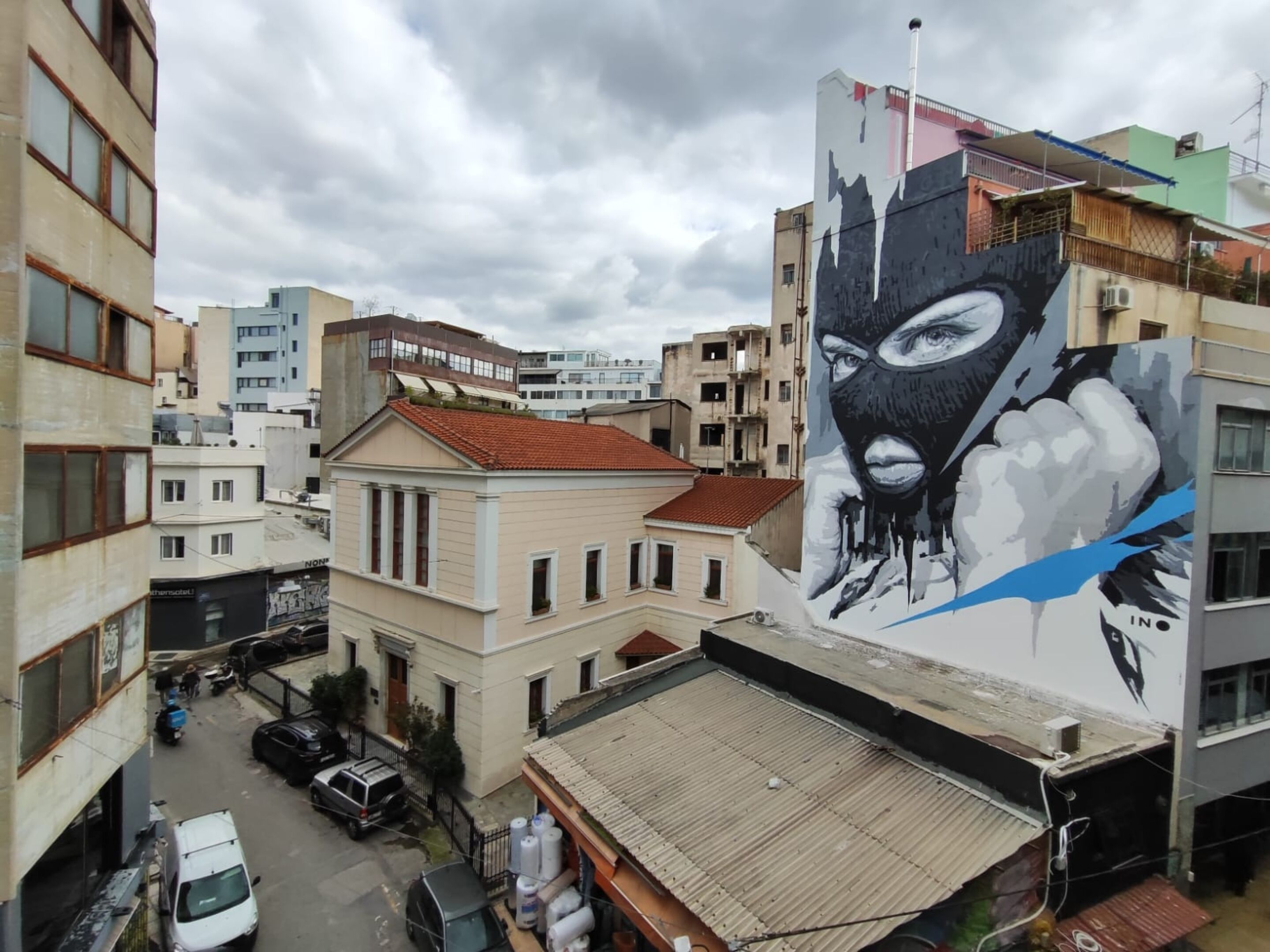 A building with a large mural of a masked figure on its side.