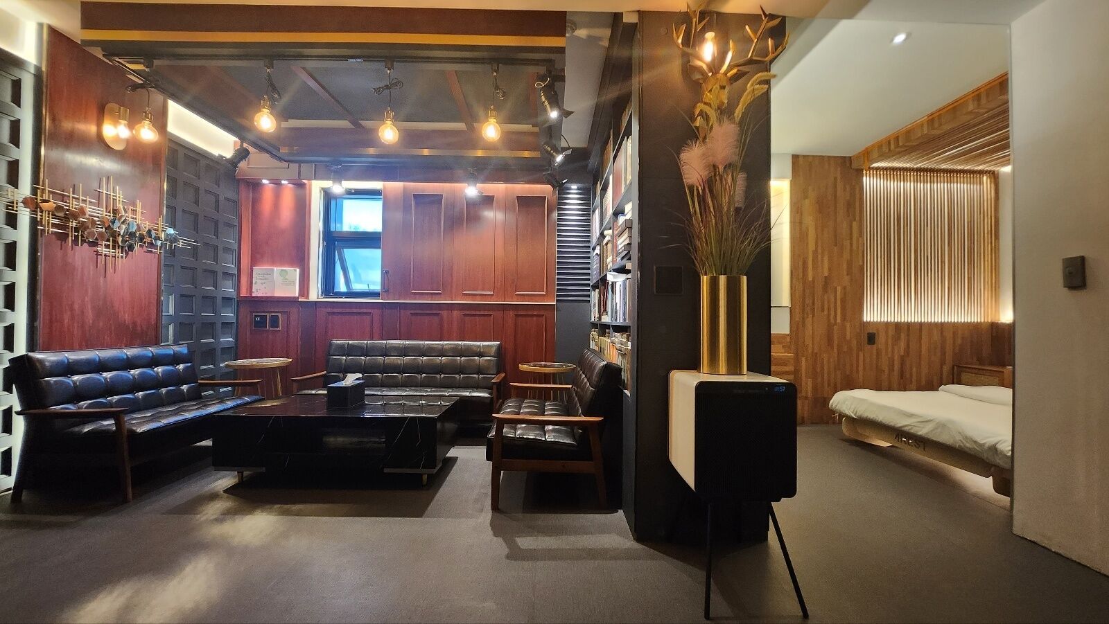 A modern hotel lobby with leather seating, a fireplace, and a bookshelf.
