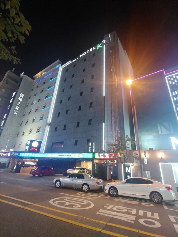 Un hôtel à étages, doté d’une enseigne lumineuse et d’un parking avec des places délimitées.