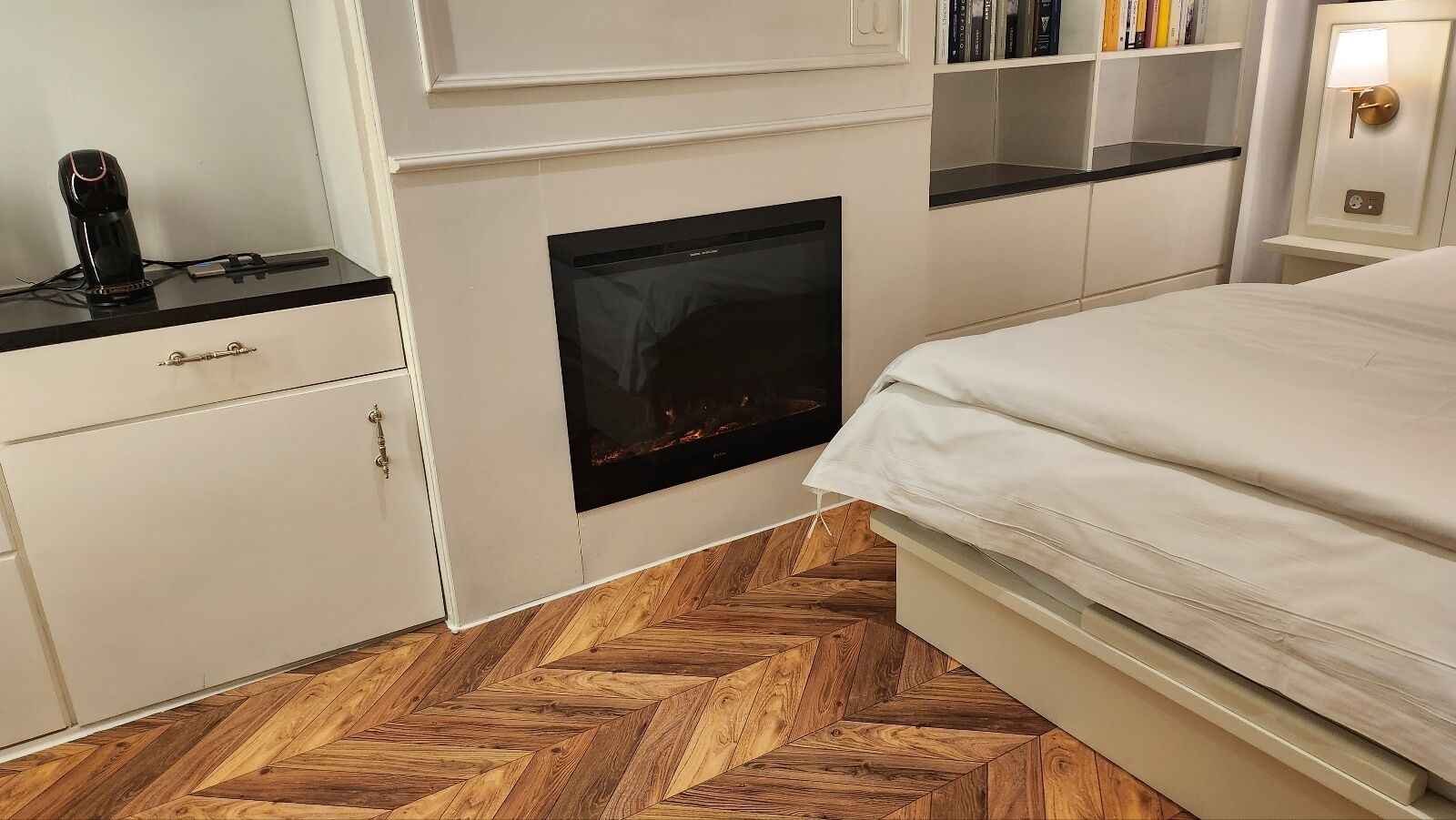 Un dormitorio con chimenea, una cama, una mesita de noche y una estantería.