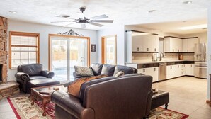 A spacious living room with leather sofas, a fireplace, and a kitchen in the background. - Home with play room, enclosed pool . Only 10 minutes from the beach! (Vero Beach)