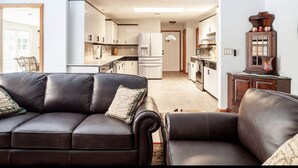 A modern living room with a black leather sofa and a wooden cabinet with decorative items. - Home with play room, enclosed pool . Only 10 minutes from the beach! (Vero Beach)