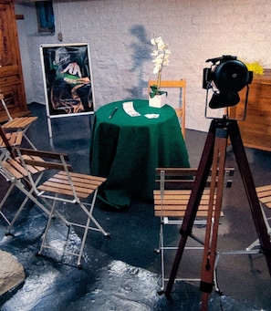 Une pièce avec une table verte, des chaises, un trépied et une affiche accrochée au mur.