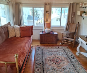 Una habitación acogedora con una cama grande, una mesita de noche de madera, una silla y vistas al exterior.