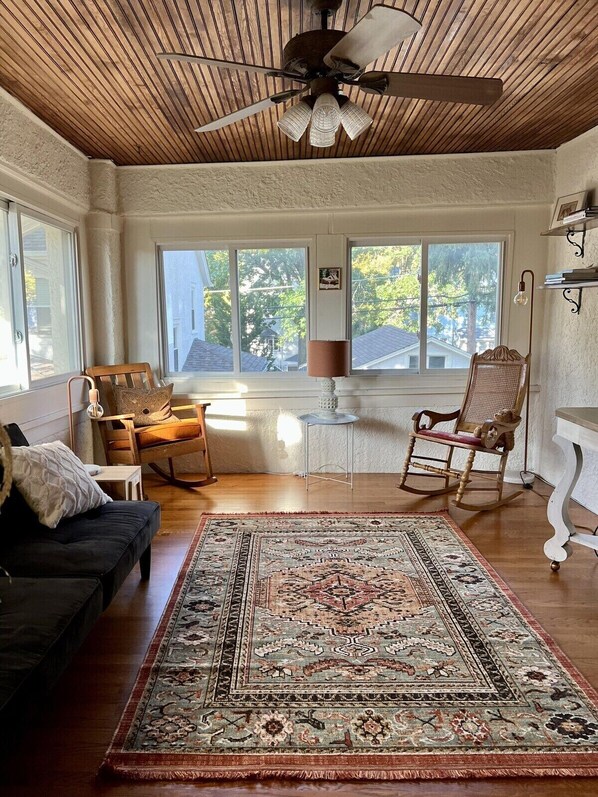 A cozy living room with a ceiling fan, a large rug, and a rocking chair.