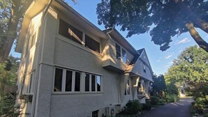 Ein zweistöckiges Haus mit geneigtem Dach, großen Fenstern und einer Auffahrt.