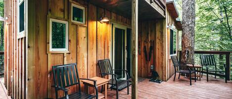 Une cabane en bois avec une terrasse, deux chaises et une table.