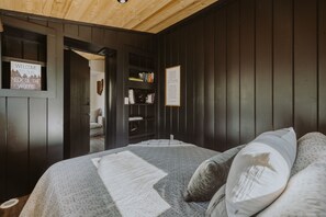 A cozy bedroom with a bed, a bookshelf, and a welcome sign. - The White Oak Treehouse | Hocking Hills (South Bloomingville)