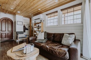 Ein gemütliches Wohnzimmer mit brauner Ledersofa, Holzboden und weißen Wänden.