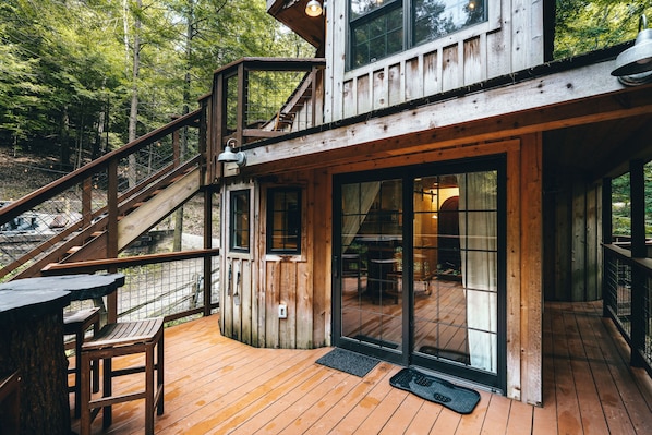 A wooden cabin with a deck, a staircase, and a large sliding glass door.