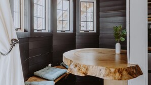 A cozy room with a curved wooden bench, large windows, and a potted plant. - The Beech Treehouse | Hocking Hills (South Bloomingville)