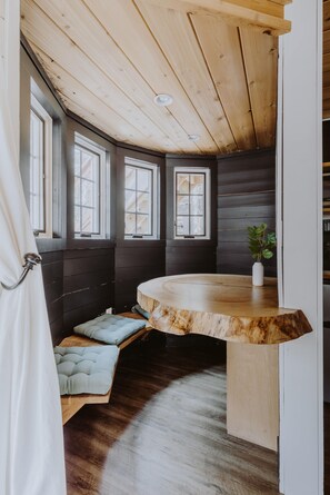 Una habitación acogedora con un banco de madera curvo, ventanas amplias y una planta en maceta.