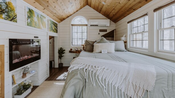 Une chambre confortable avec un plafond en pente, une grande fenêtre, un téléviseur et une cheminée.