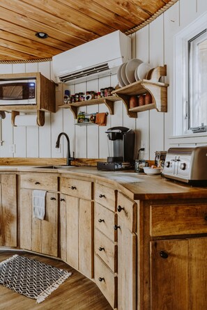 A wooden kitchen with a built-in microwave, a coffee maker, and a toaster.