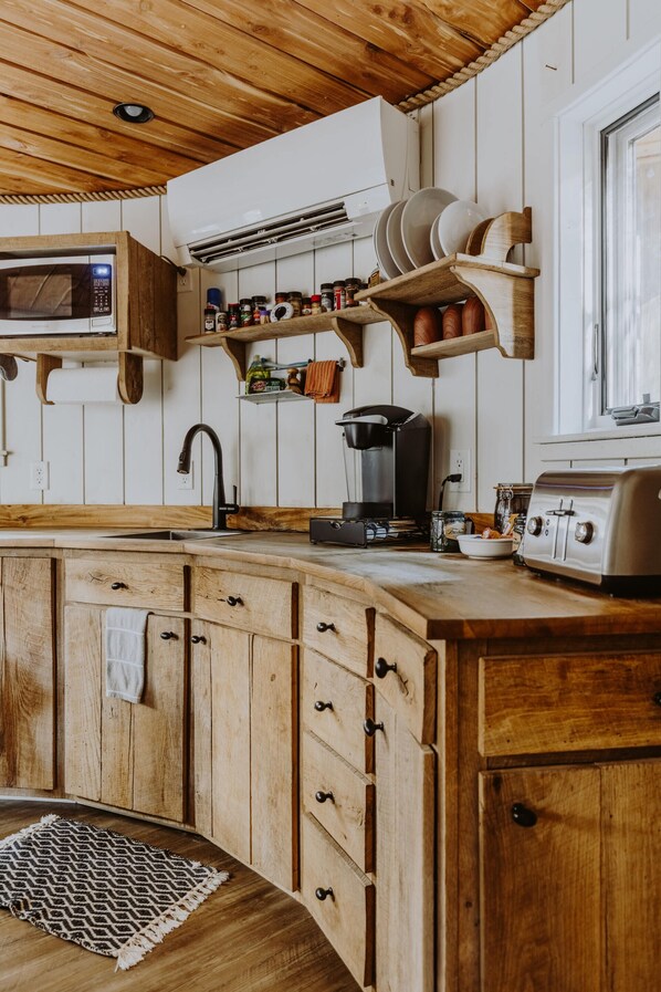 Puisesta materiaalista valmistettu keittiö, jossa on sisäänrakennettu mikroaaltouuni, kahvinkeitin ja leivänpaahdin.