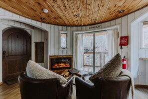 A cozy room with a fireplace, leather chairs, and a wooden ceiling.