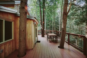 Eine Holzterrasse mit Tisch und Stühlen, umgeben von Bäumen.