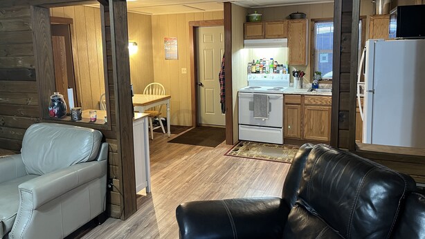A cozy cabin interior with a dining area, kitchen, and seating space. - CABIN IN THE WOODS, 10 acres, Sleeps 8. Close to ORV trails and Forest Dunes. (Roscommon)