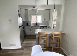 A modern kitchen with white cabinets, a central island, and two wooden bar stools. - Brookfield Boutique Charmer (Brookfield)