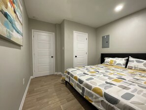 A bedroom with a bed, two doors, and a ceiling light.