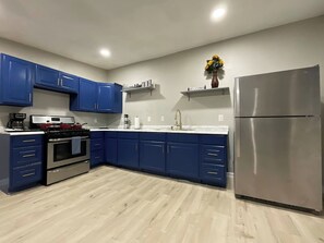 A modern kitchen with blue cabinets, a stainless steel refrigerator, and a built-in oven.