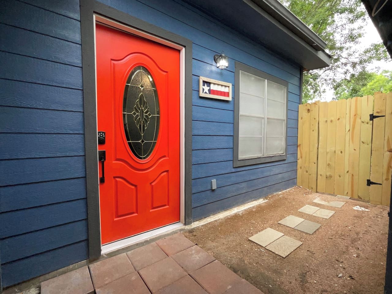 A house with a red door, a blue exterior, and a wooden fence.