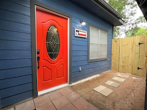Una casa con puerta roja, fachada azul y cerca de madera.
